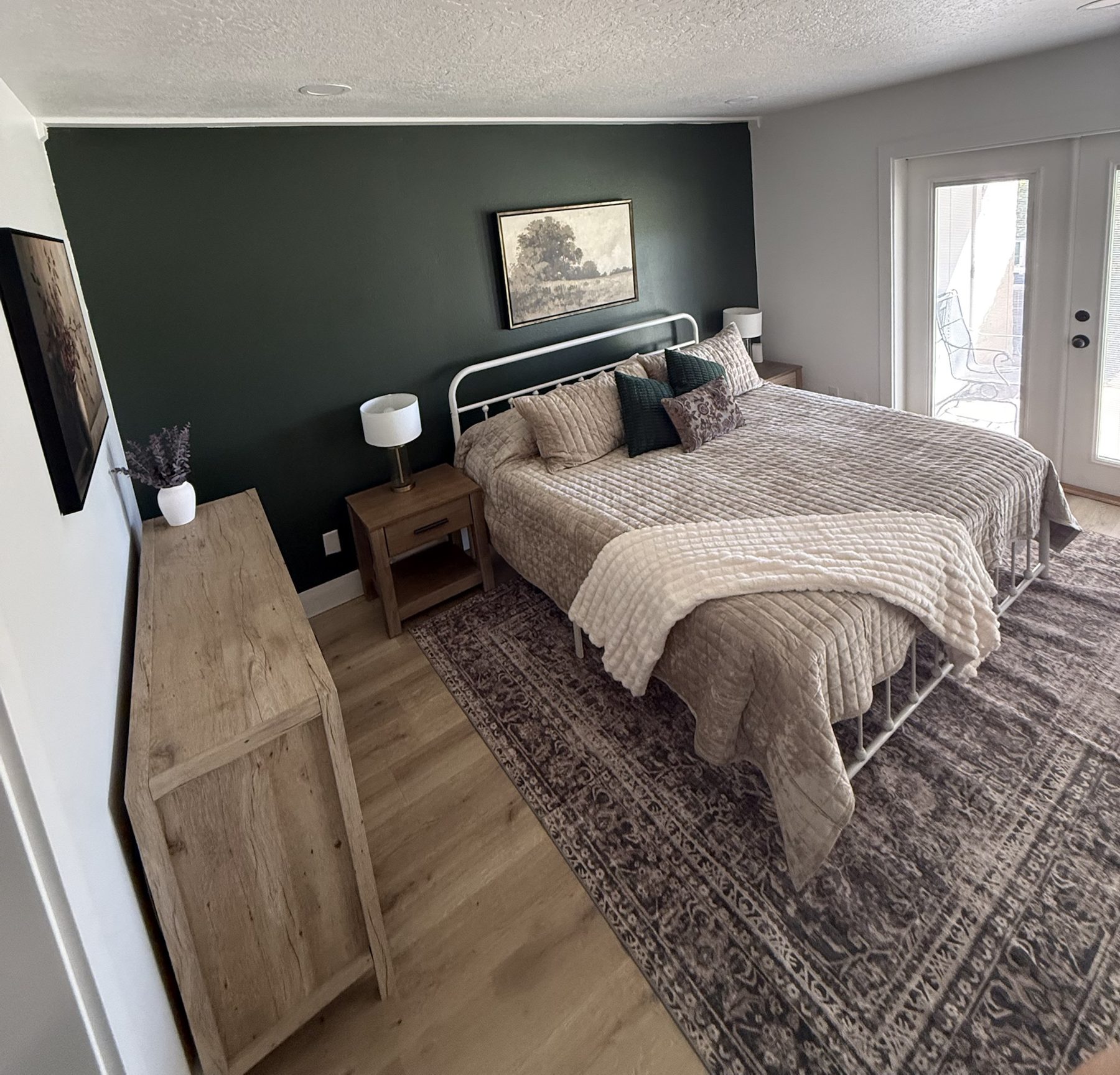 King bedroom with green accent wall and patio doors