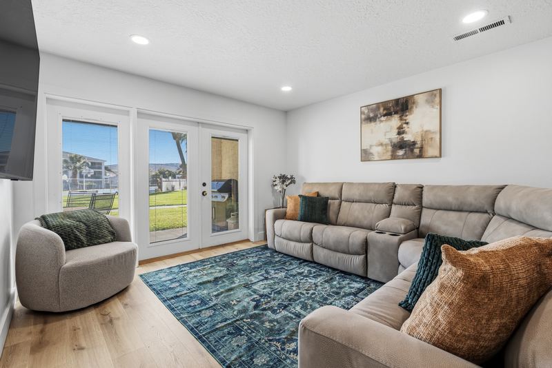 Living room with a large reclining sectional, swivel chair, and French doors opening to the patio