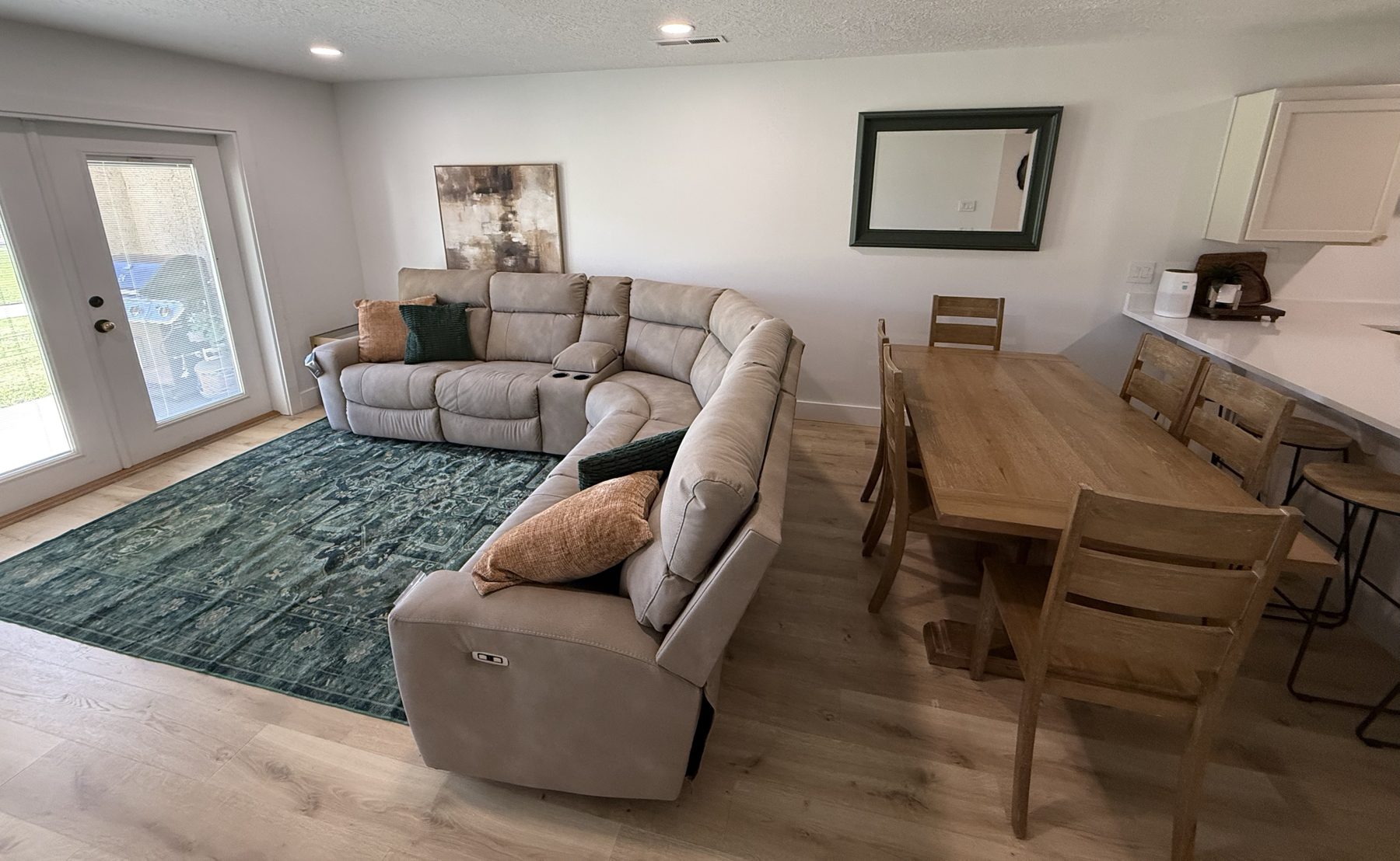 Living room with reclining sectional, dining table for ten, and French doors to the patio